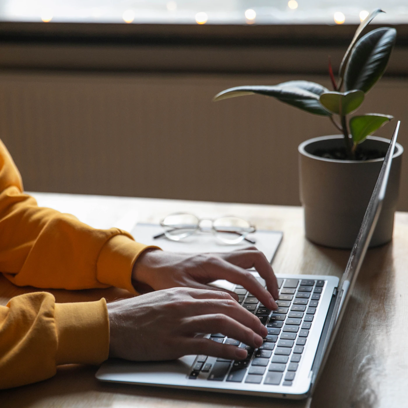 A laptop on a tidy desk beside a small green plant, a calm private workspace where a screening is completed