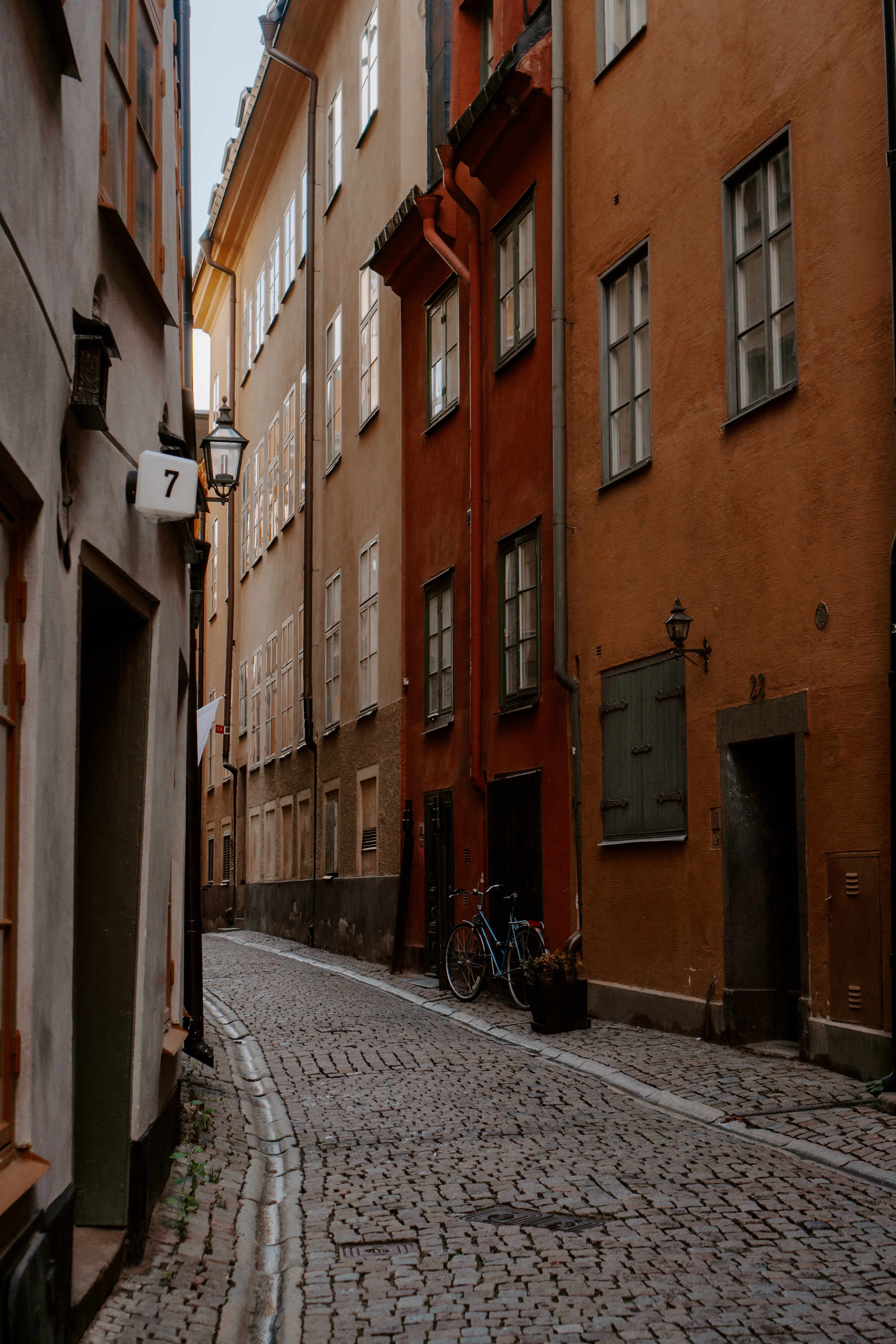 A bicycle leans against an orange building on a narrow cobblestone alley in Gamla Stan.