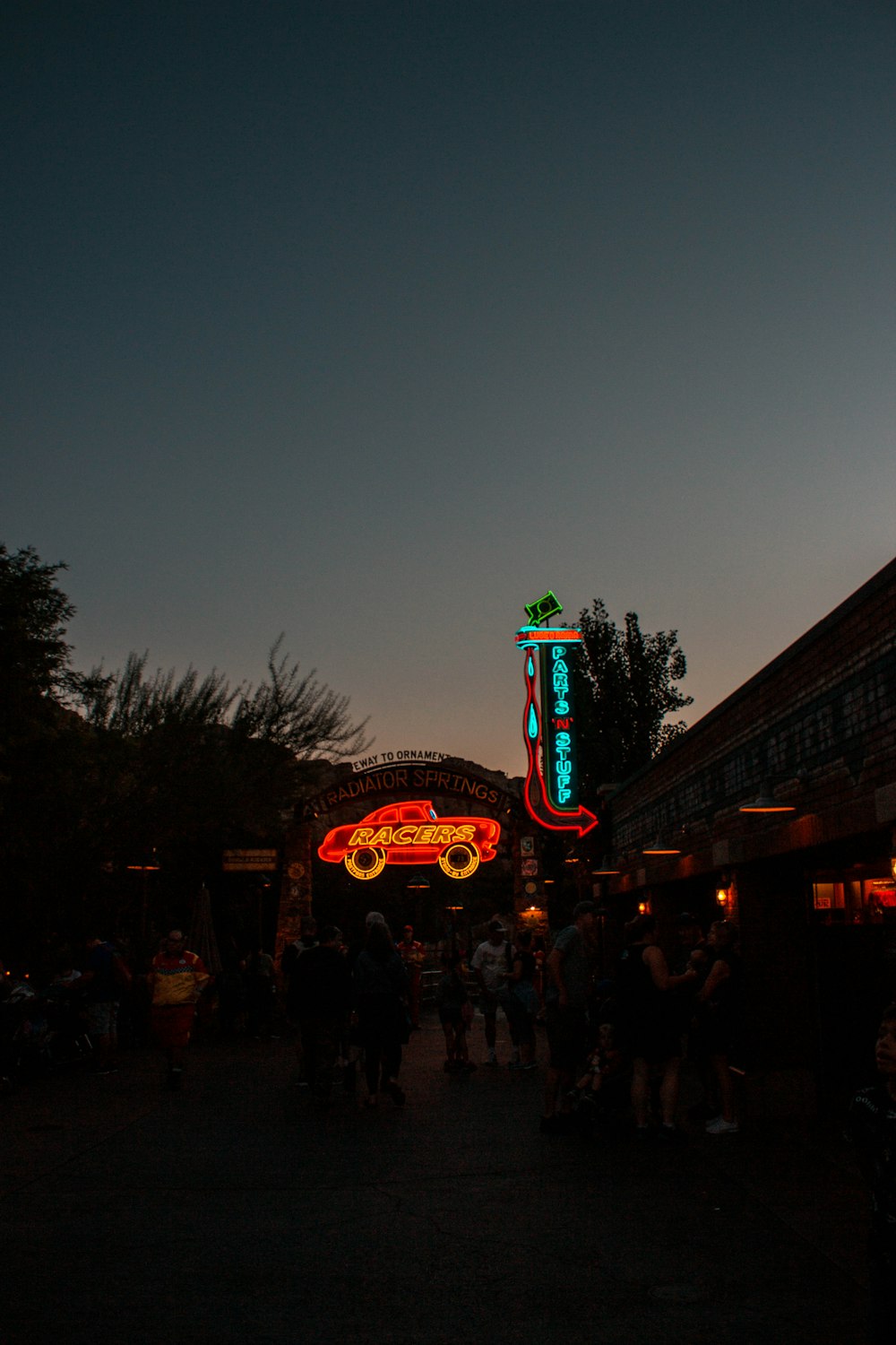 a group of people standing outside a building with a neon sign