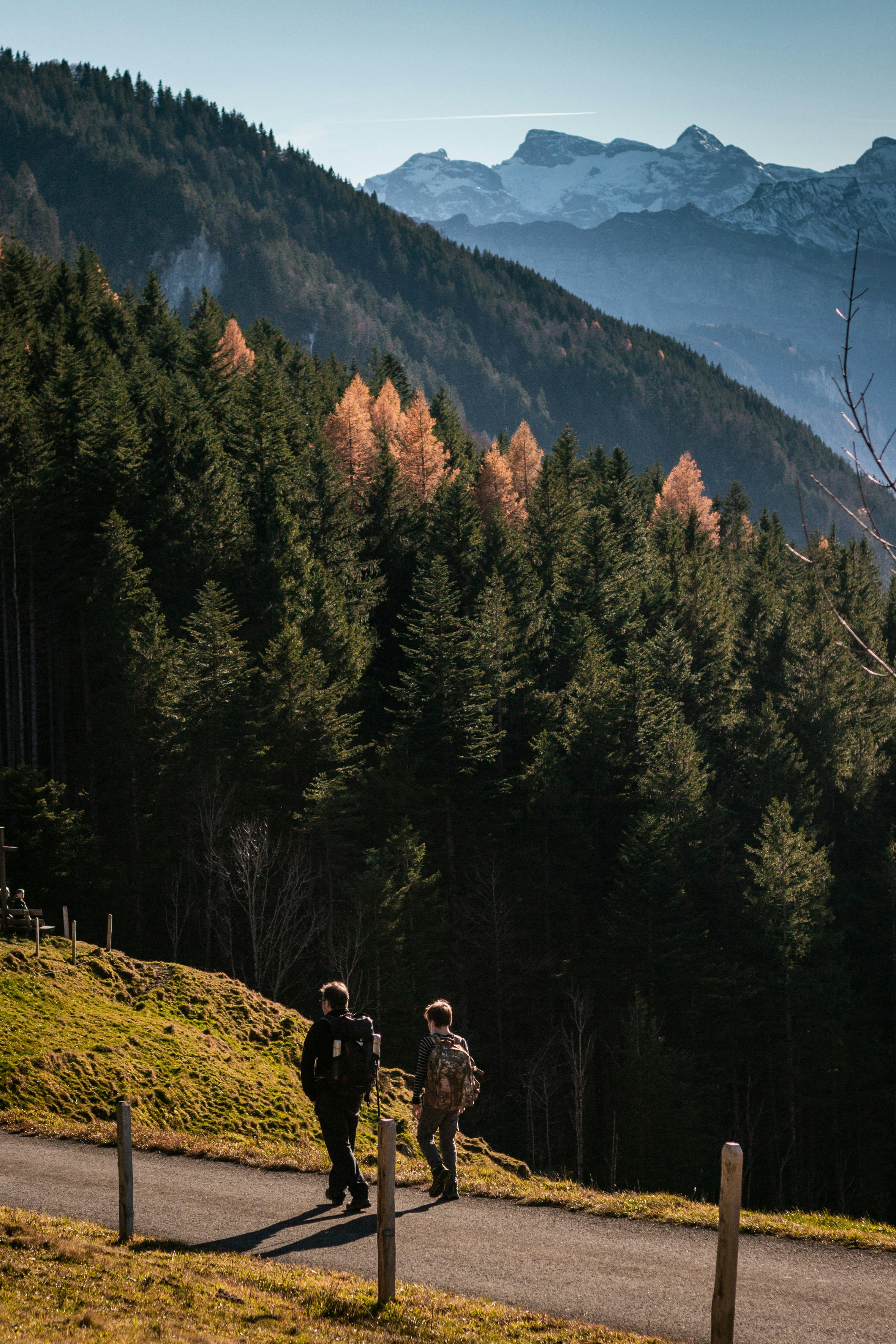 two people walking on a trail in the mountains