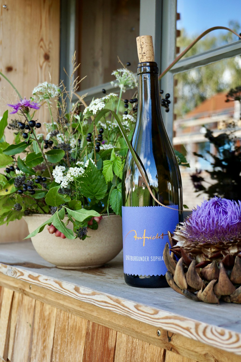 a bottle of wine next to a potted plant