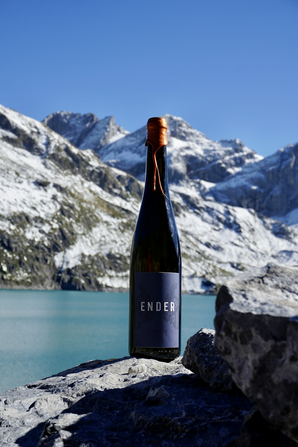 a bottle of wine on a rocky surface with mountains in the background