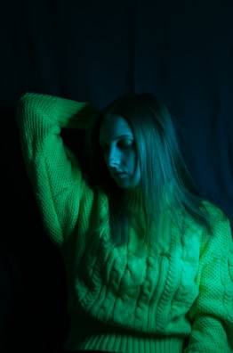 Harvey in his green cardigan, striking a thoughtful pose against a simple pastel background.