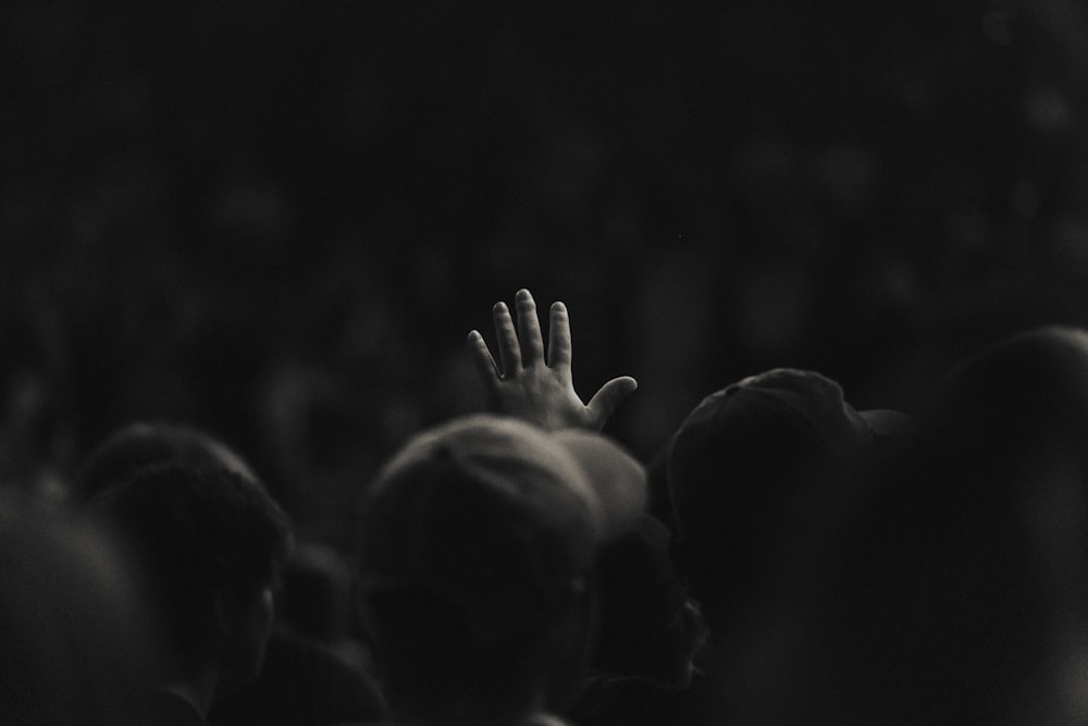 a person holding their hand up in the air in front of a crowd