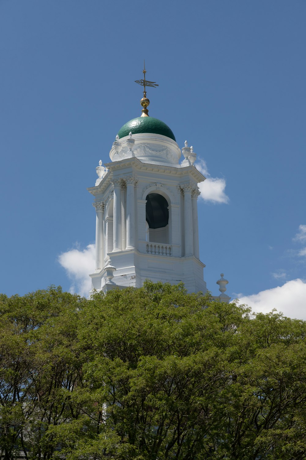 a white building with a green dome and a cross on top