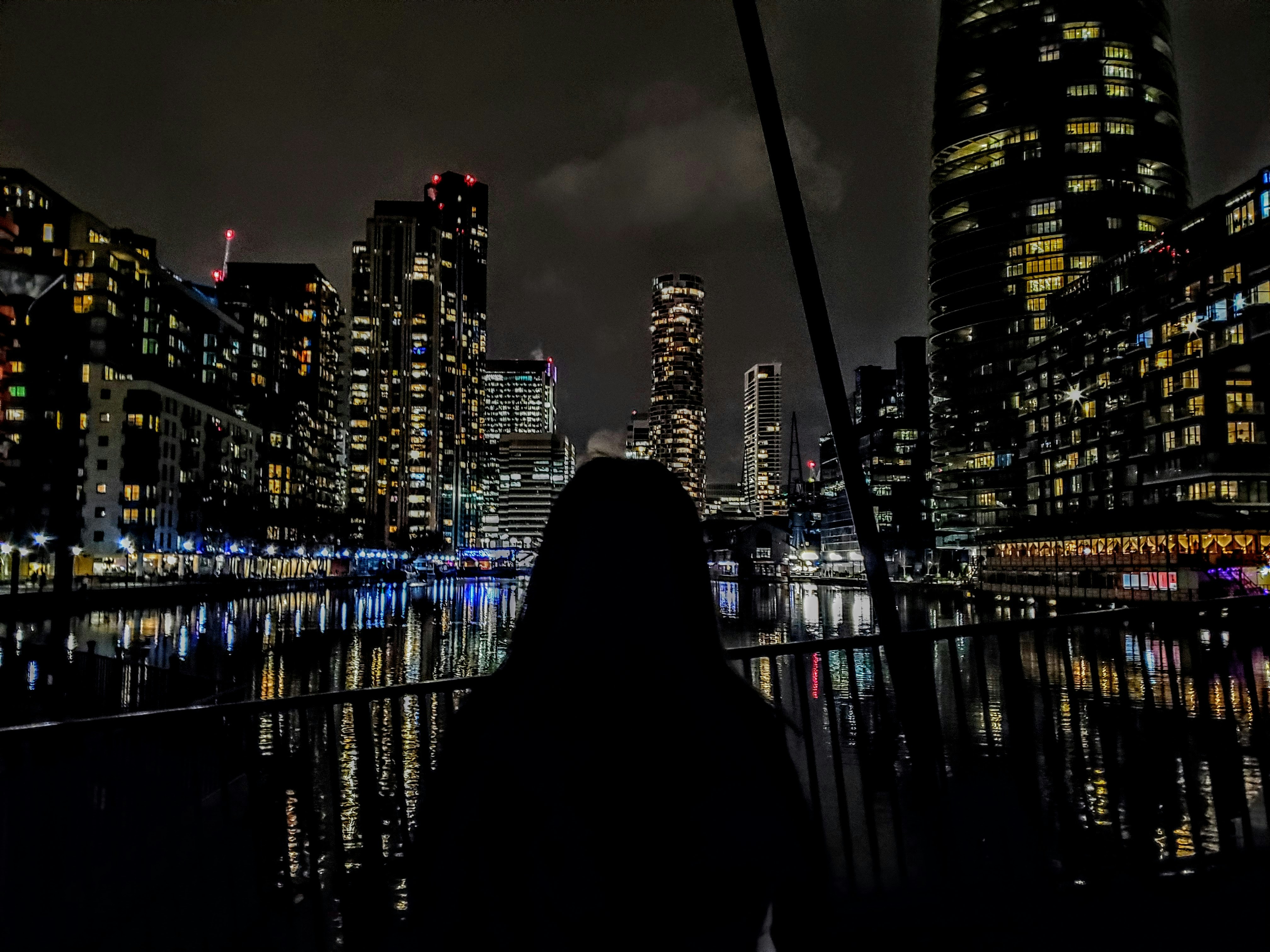 a person sitting on a dock looking out at a city at night