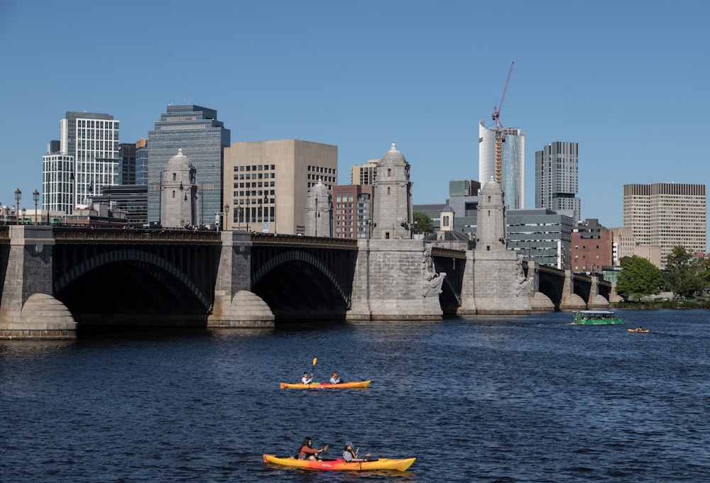 a group of people in kayaks in front of a bridge