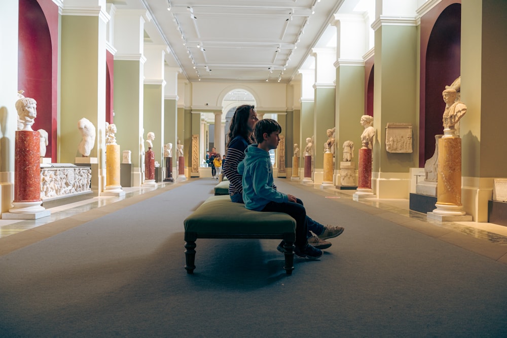 a man and woman sitting on a bench in a museum