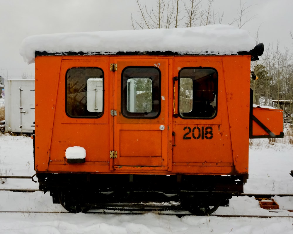 an orange train car covered in snow