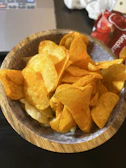 Golden potato chips sprinkled with sea salt on a wooden table.