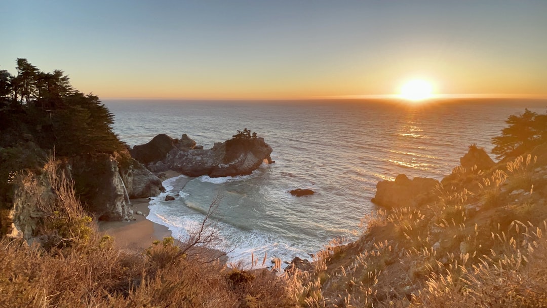 a beach with rocks and water, Sunset
