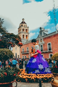 Statue of Shakira in Barranquilla surrounded by colorful flowers and blue sky.