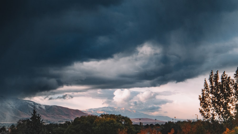 a cloudy sky over trees and mountains