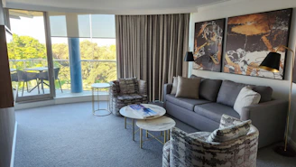 Interior view of a stylish, modern living room with gold accents and large windows.