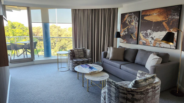 Interior view of a stylish, modern living room with gold accents and large windows.