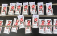 Several rows of paper tickets are arranged on a flat dark surface. Each ticket features a prominent red design with text and barcodes. The tickets are grouped in sets with handwritten labels above them, displaying numbers like '5218', '5216', and others.