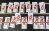 Several rows of paper tickets are arranged on a flat dark surface. Each ticket features a prominent red design with text and barcodes. The tickets are grouped in sets with handwritten labels above them, displaying numbers like '5218', '5216', and others.