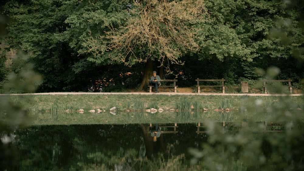 a person sitting on a bench by a lake