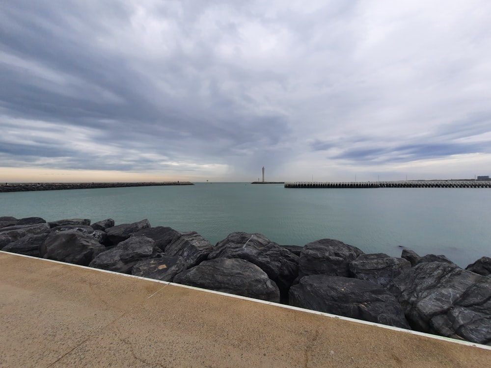 a rocky beach with a pier in the distance