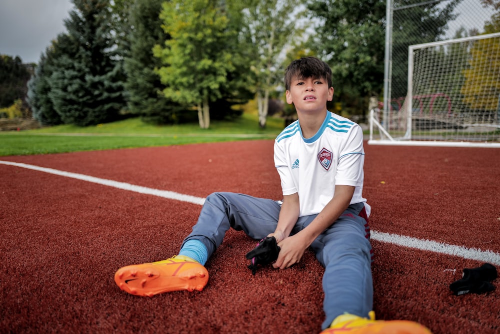 a boy sitting on a baseball field