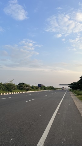 Modern truck driving on a highway surrounded by green fields under a clear blue sky