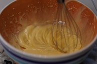 A bowl of brownie batter being mixed with a wooden spoon, showing the smooth texture without eggs.