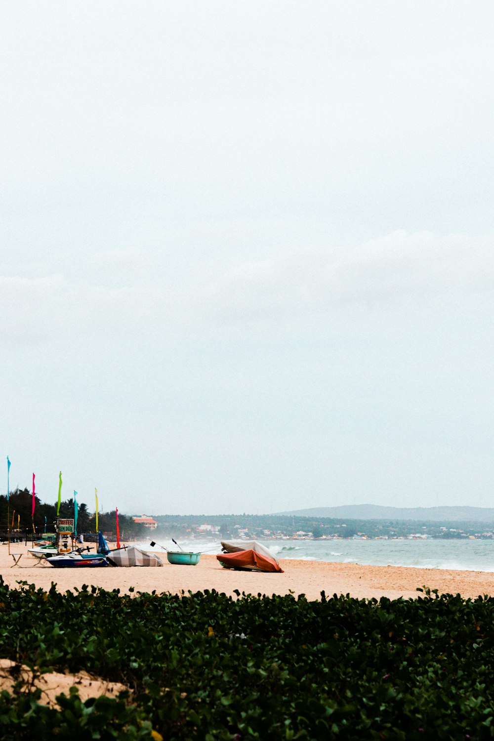 a beach with boats and a body of water in the background