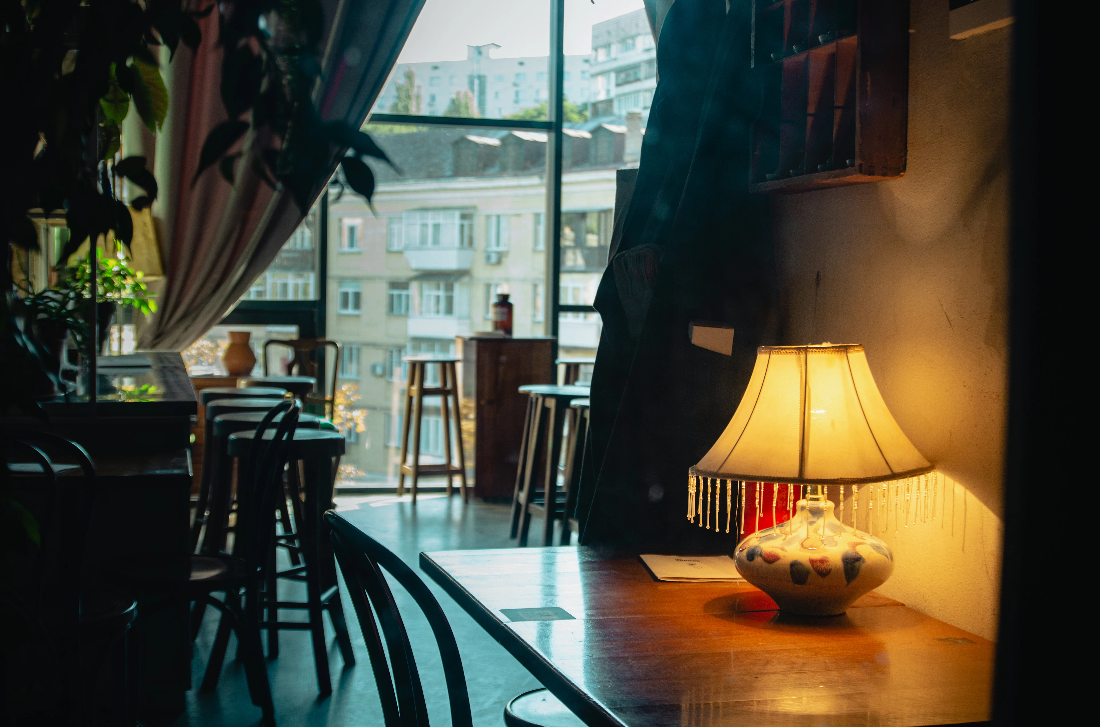A table with a lamp and chairs by a window