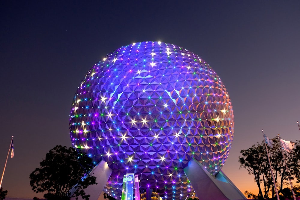 a large ferris wheel at night with Epcot in the background