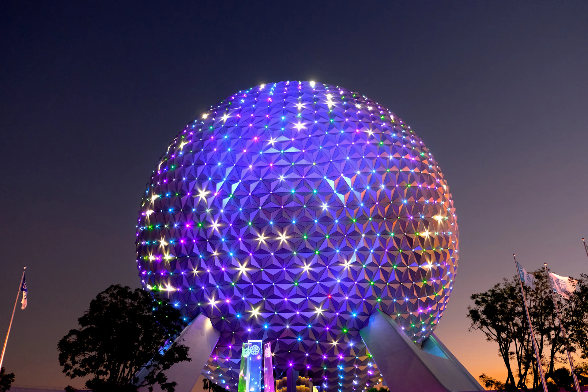 a large ferris wheel at night with Epcot in the background