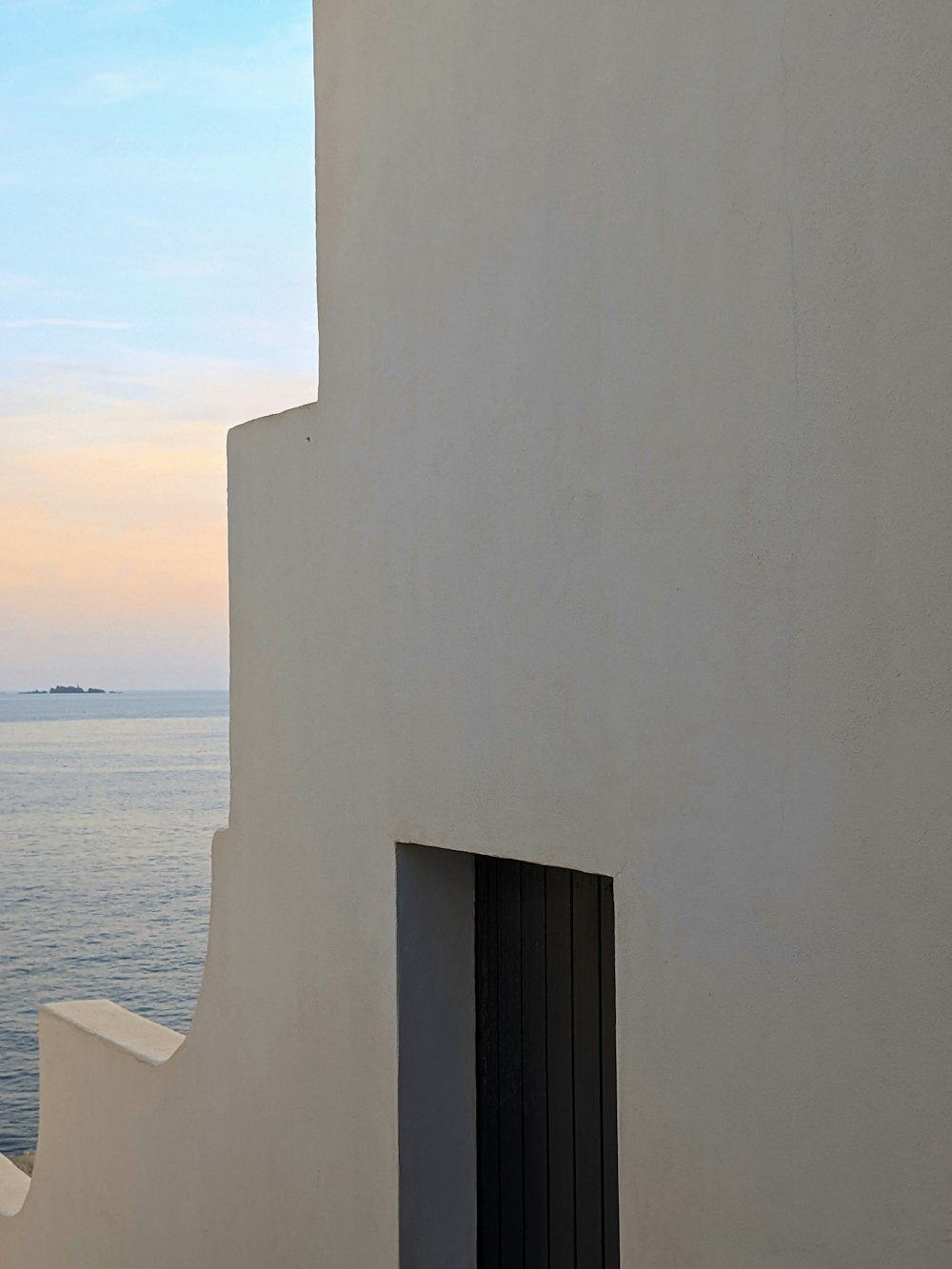 a building with a door and a body of water in the background