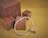 A silver bracelet adorned with charms is placed on a set of wooden blocks against a yellow background. The bracelet has a cubic metallic clasp and features an intricate bird charm.