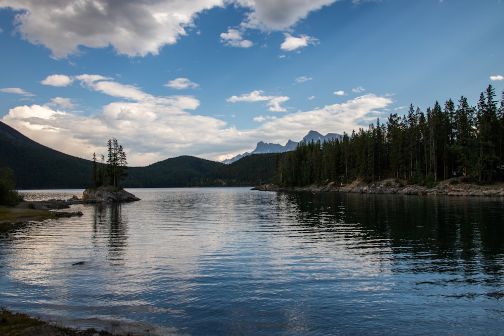 a lake with trees and mountains in the background