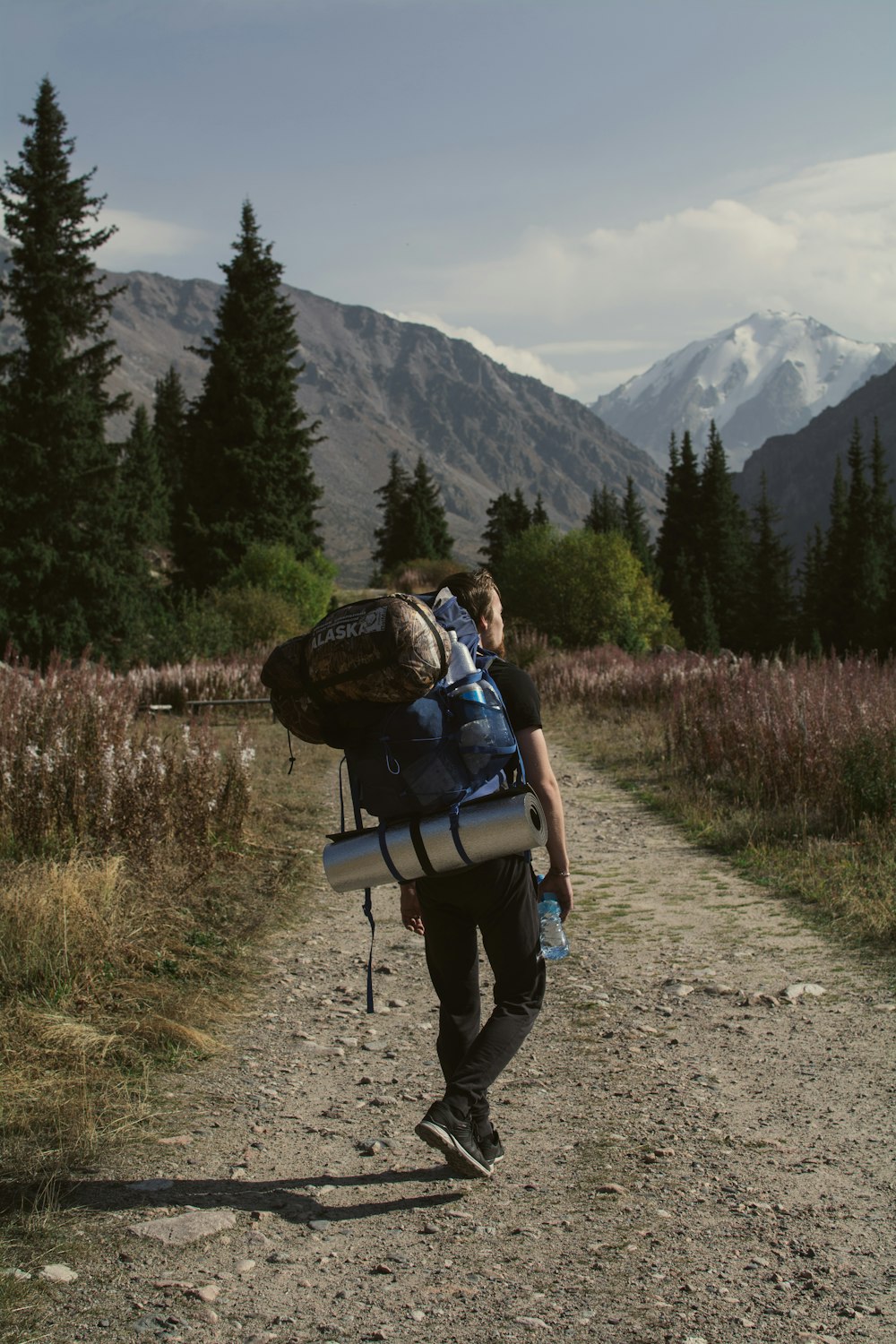 a man with a backpack walking on a trail in the mountains