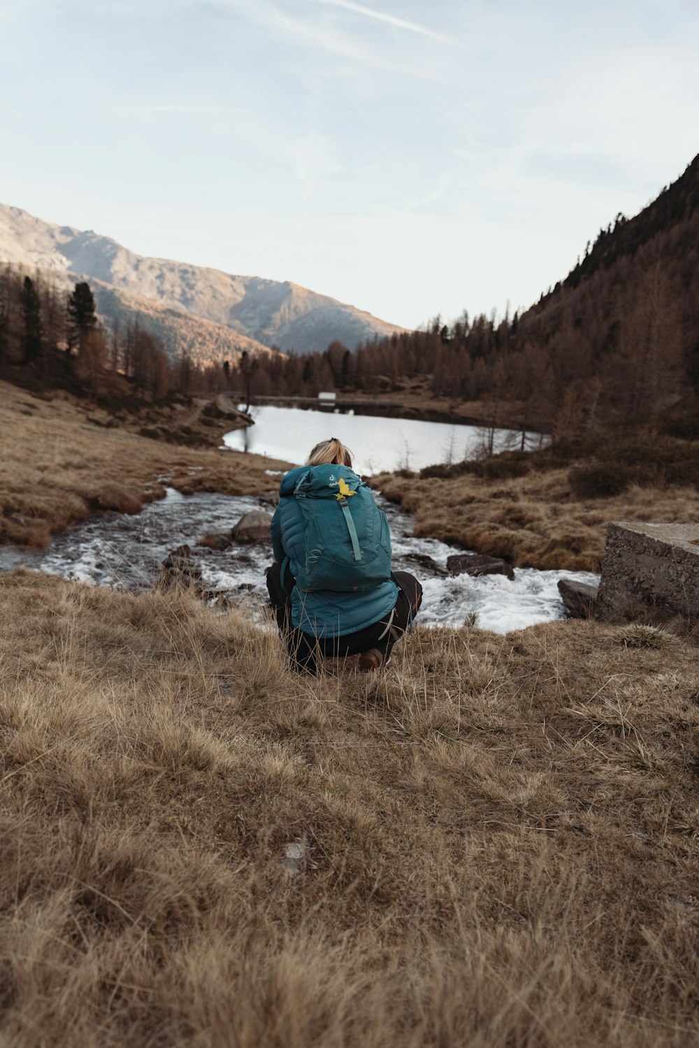 a person sitting on a rock looking at a lake