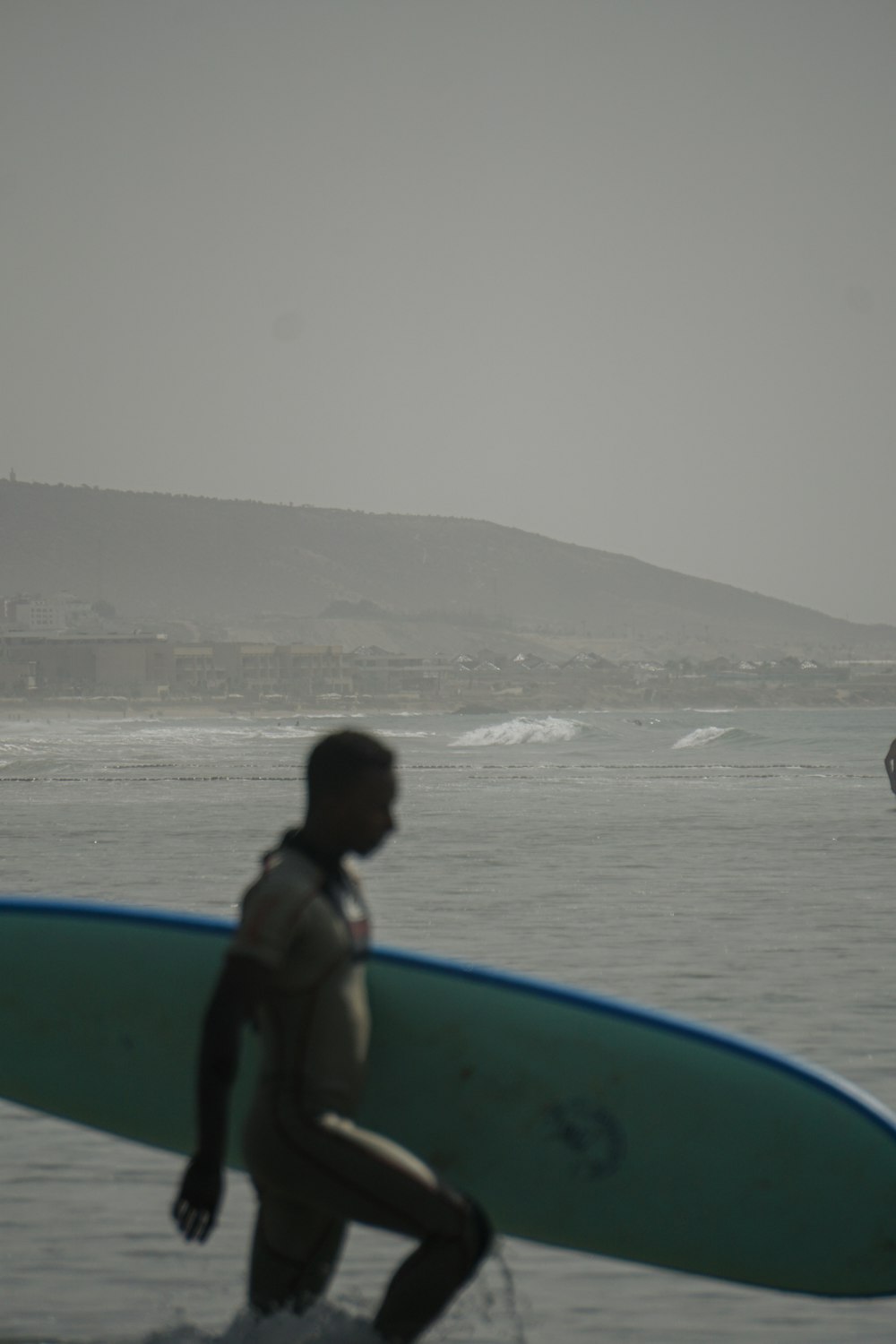 a person carrying a surfboard on a beach