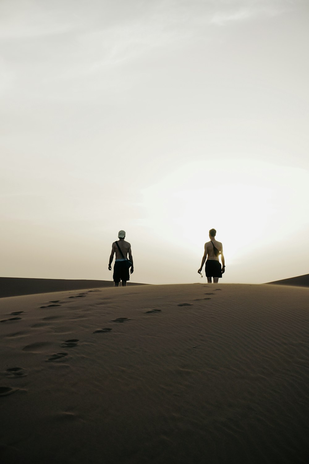 two people walking on a sandy beach