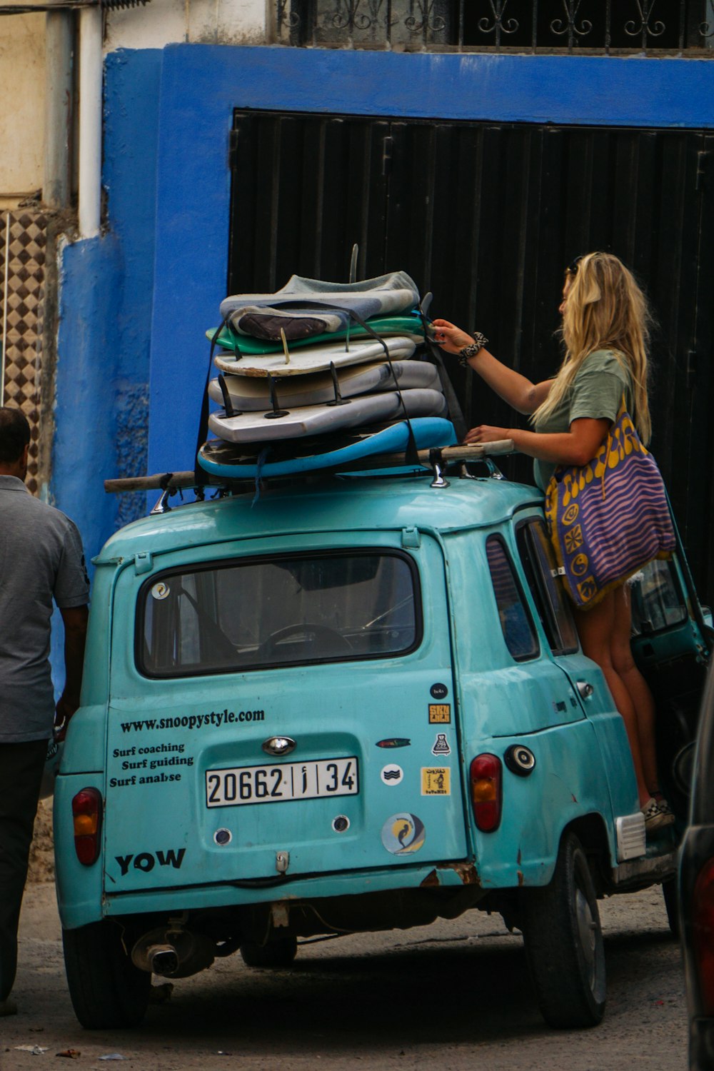 a person standing on the back of a van with luggage on top