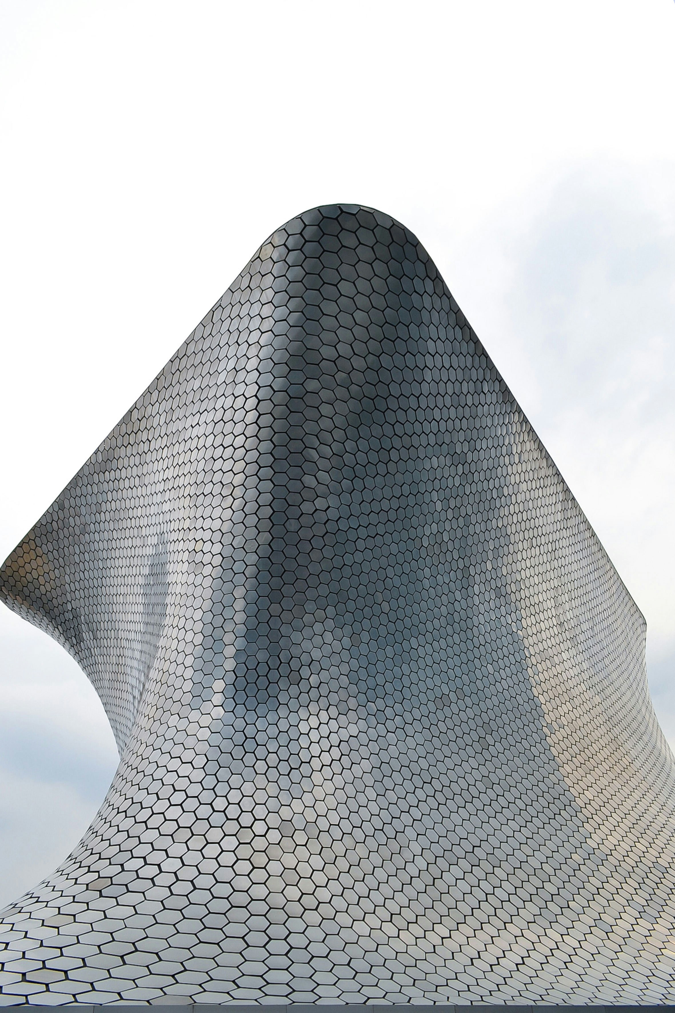a close-up of a grey stone sculpture with Museo Soumaya in the background