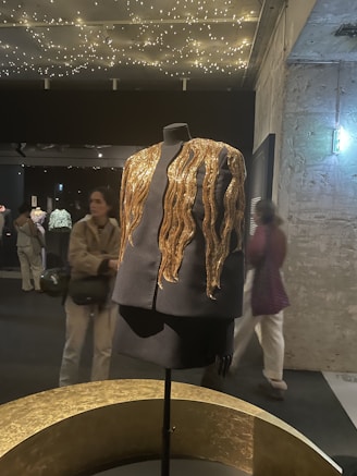 A sleek black and gold professional uniform displayed on a mannequin.