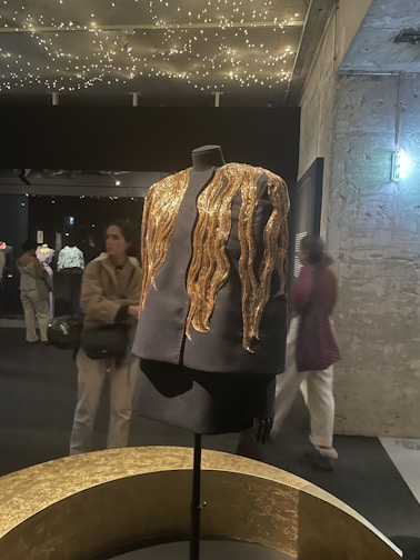 A sleek black and gold professional uniform displayed on a mannequin.