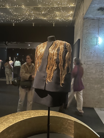 A stylish crowd enjoying a Maansarovar exhibition event with gold and white decor.