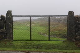 a fenced off area with a grassy field and rocks in the background