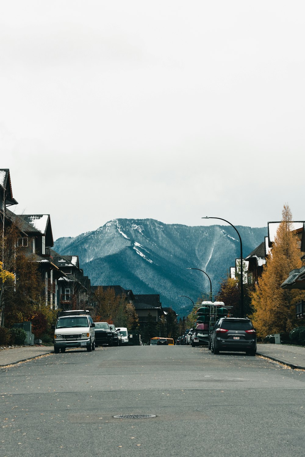 uma rua com carros e edifícios e uma montanha ao fundo