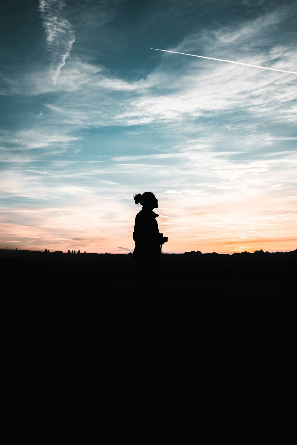 a silhouette of a person standing in front of a sunset