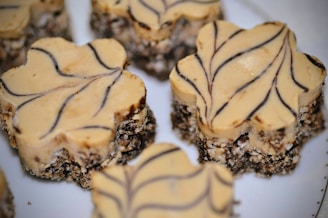Several dessert bars with a creamy beige top layer decorated with dark brown swirl patterns. The base appears to be a crumbly mix of chocolate and oats, providing a rustic texture.