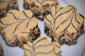 Several dessert bars with a creamy beige top layer decorated with dark brown swirl patterns. The base appears to be a crumbly mix of chocolate and oats, providing a rustic texture.