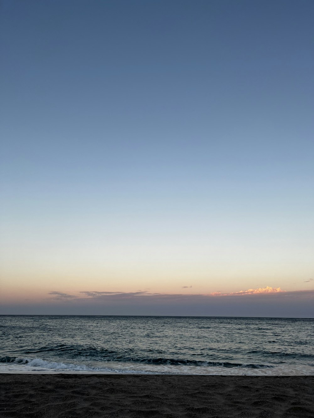 a beach with a body of water and a blue sky