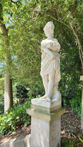 Elegant marble sculpture standing gracefully in a sunlit garden.