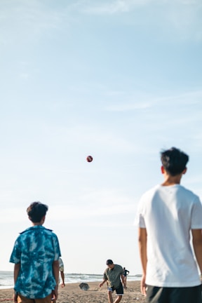 A group of friends playing beach volleyball under a sunny sky.